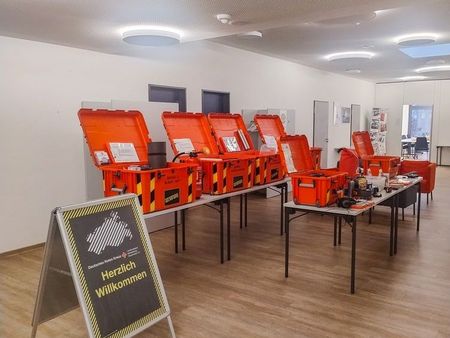 Sechs große rote Kunststoffkisten stehen aufgeklappt auf mehreren Tischen.