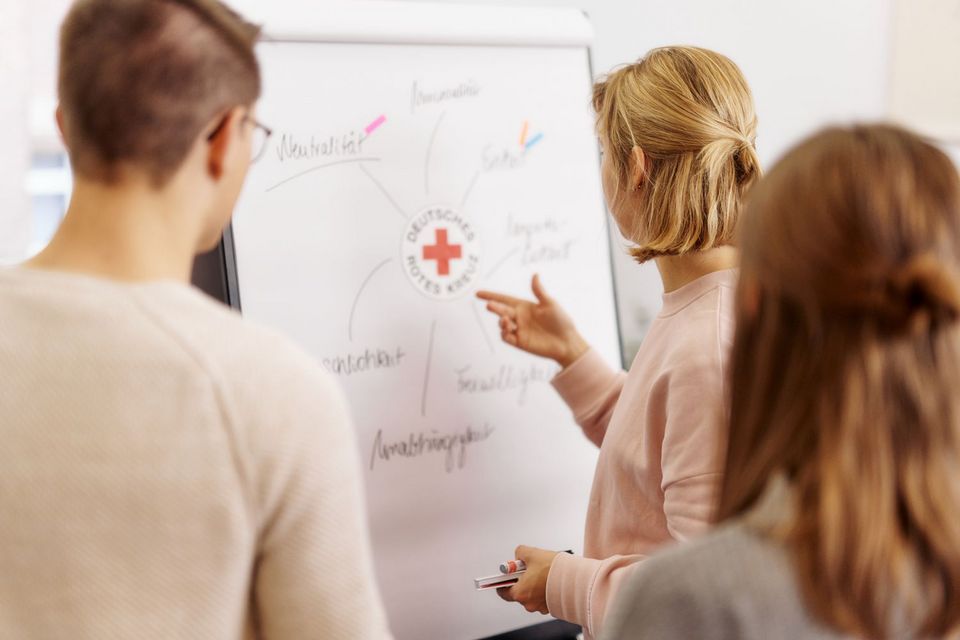 Drei DRK-Mitarbeitende stehen an einem Whiteboard